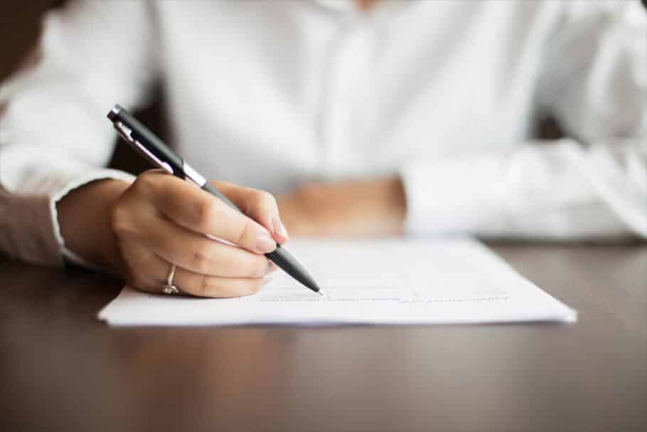 Hand Of Businesswoman Writing On Document At Table