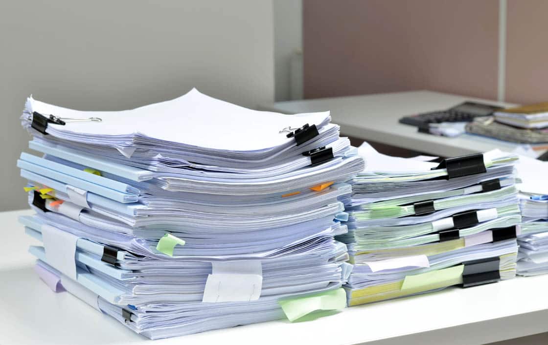 Pile Of Documents On Desk At Workplace